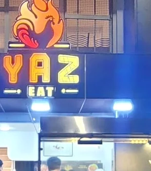 Détail recadré de l’enseigne publique Yaz Eat